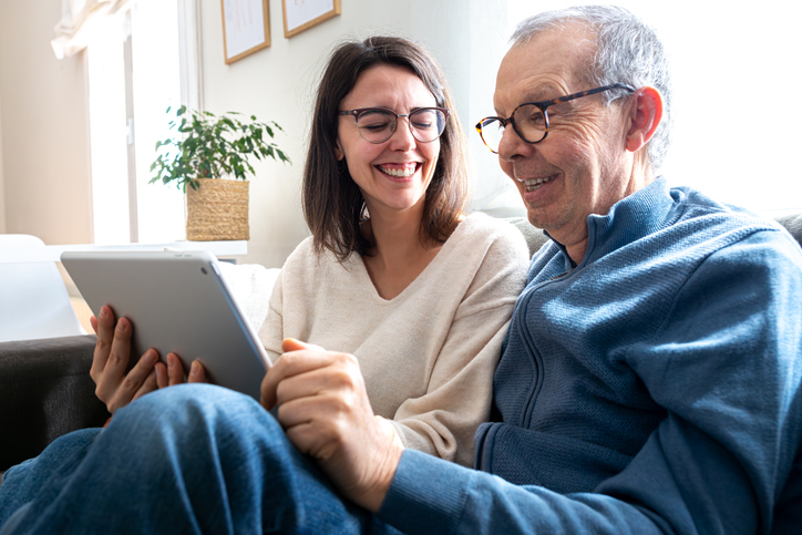 Older adult man browses senior living communities with adult daughter.