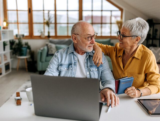 Senior couple making online reservation using laptop at their home