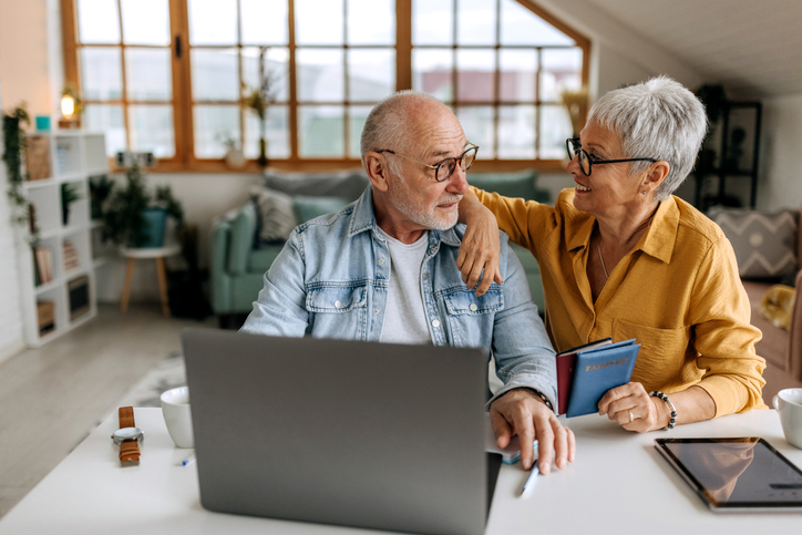 Senior couple making online reservation using laptop at their home