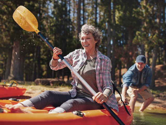 Senior man and woman setting out in a kayak from shore