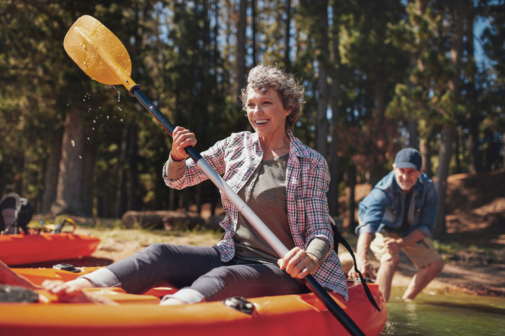 Senior man and woman setting out in a kayak from shore