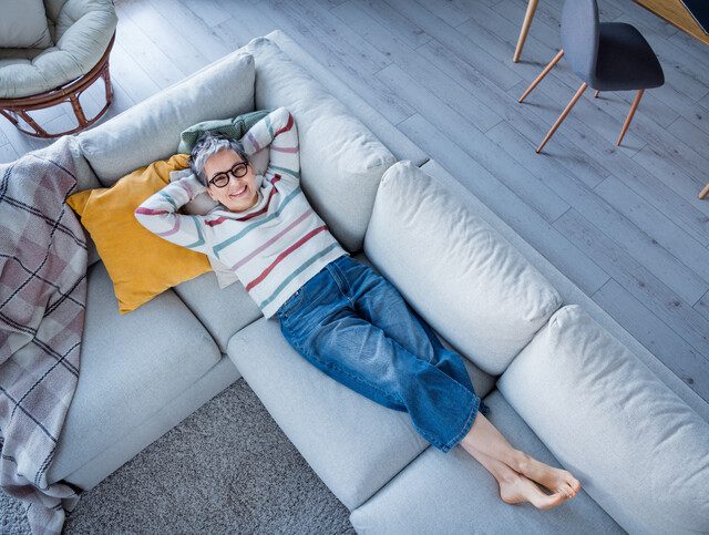 older adult woman relaxing on her couch with her feet crossed