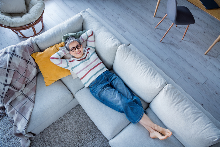 older adult woman relaxing on her couch with her feet crossed