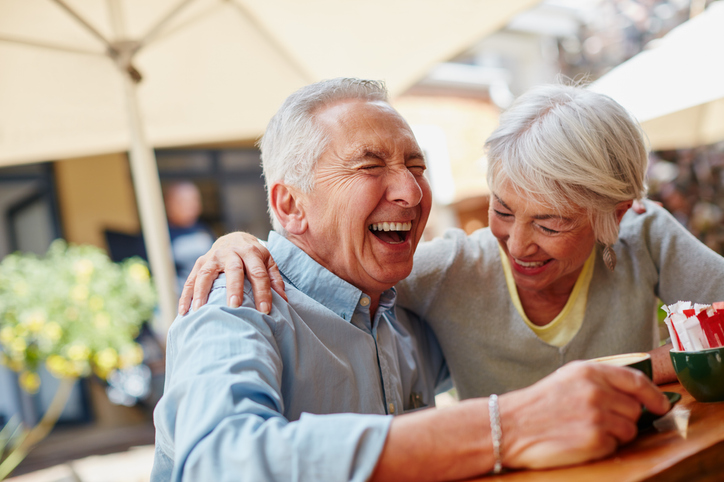 senior couple laughing and enjoying a meal outdoors