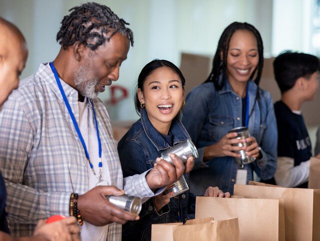 group of people of all ages packing canned food into paper bags