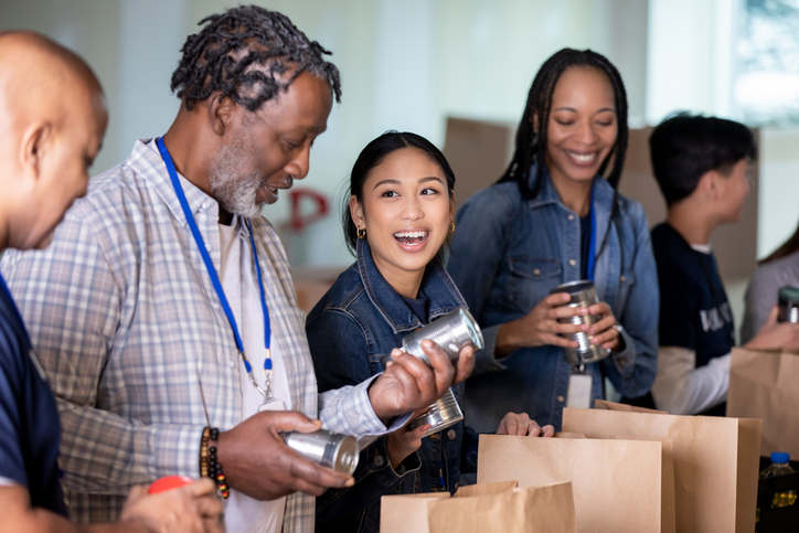 group of people of all ages packing canned food into paper bags